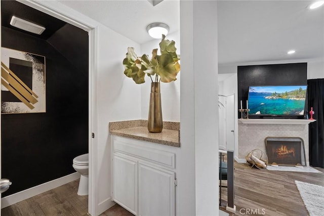 5100 Riverton Ave Unit 14, North Hollywood, CA 91601 - bathroom featuring wood finished floors, toilet, a warm lit fireplace, recessed lighting, and baseboards