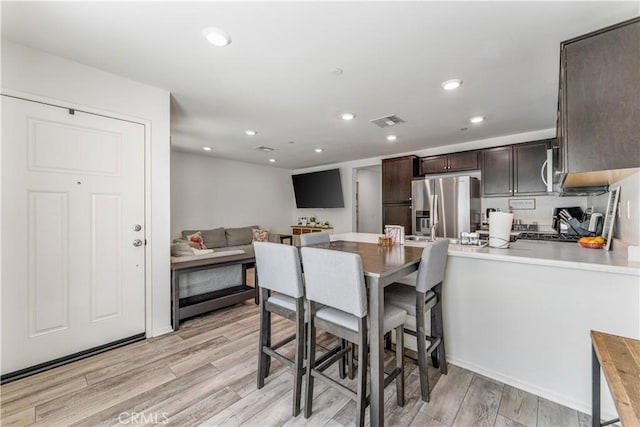 7155 Citrus Ave Unit 315, Fontana, CA 92336 - kitchen featuring stainless steel refrigerator with ice dispenser, dark brown cabinetry, a peninsula, light wood-style floors, and recessed lighting
