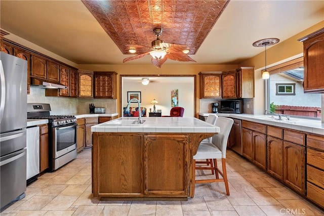 5145 Northfork Pl, Paso Robles, CA 93446 - kitchen with appliances with stainless steel finishes, a sink, under cabinet range hood, ceiling fan, and tasteful backsplash