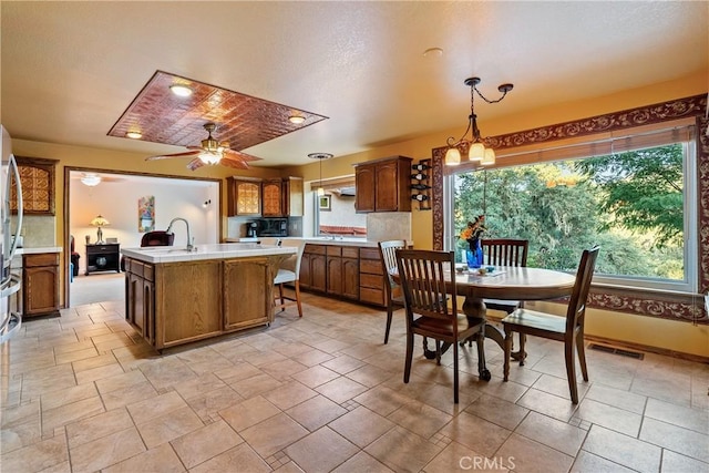 5145 Northfork Pl, Paso Robles, CA 93446 - kitchen featuring a center island with sink, light countertops, brown cabinetry, hanging light fixtures, and a sink