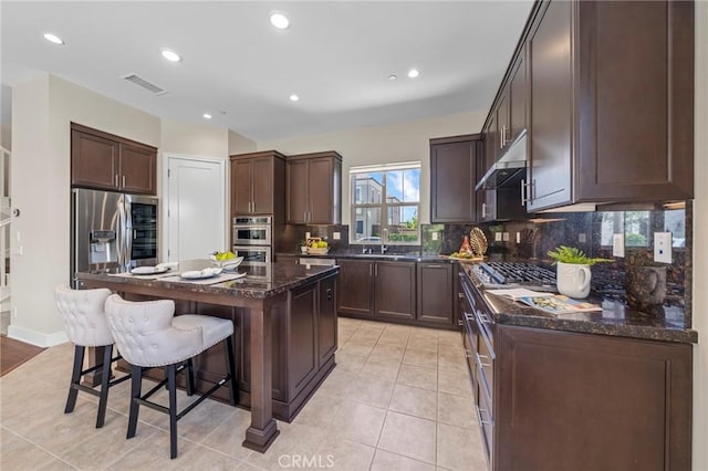 124 Trumpet Flower, Irvine, CA 92618 - kitchen with stainless steel appliances, a sink, under cabinet range hood, a breakfast bar area, and a kitchen island