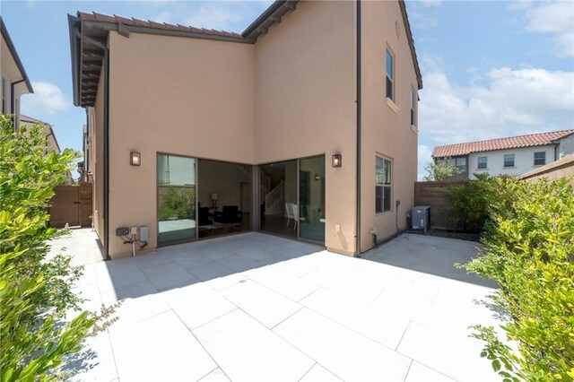 124 Trumpet Flower, Irvine, CA 92618 - back of property with stucco siding, a patio area, fence, and central AC