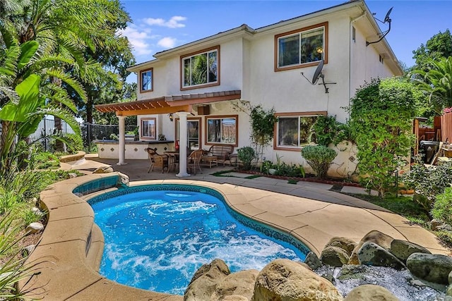 rear view of property featuring stucco siding, a patio area, a pergola, and a fenced backyard