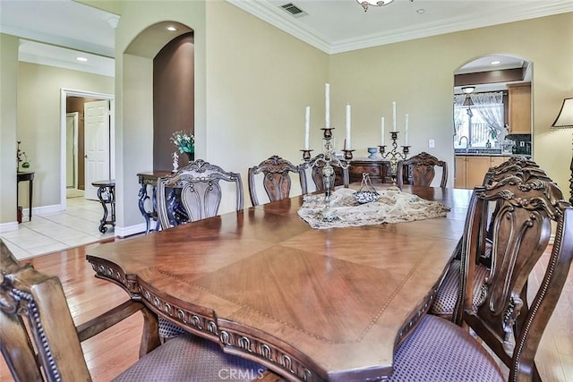dining space featuring arched walkways, crown molding, baseboards, and recessed lighting