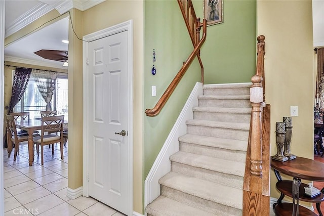 stairs with tile patterned flooring, a ceiling fan, ornamental molding, and baseboards