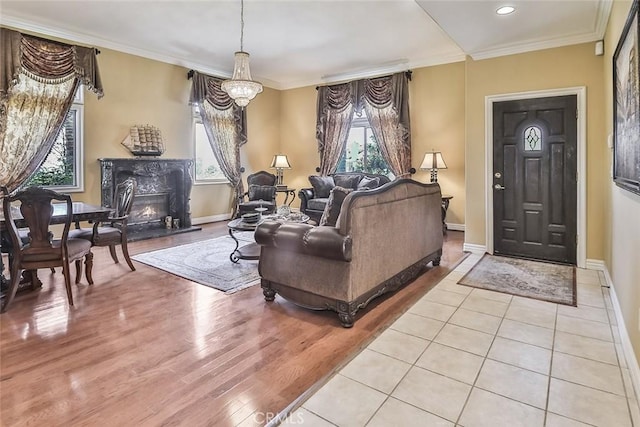 living area featuring plenty of natural light, light wood-style flooring, a premium fireplace, crown molding, and recessed lighting