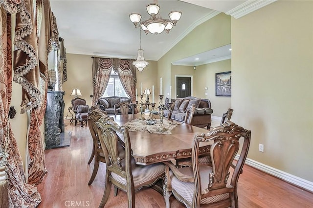 dining area featuring lofted ceiling, a chandelier, wood finished floors, ornamental molding, and baseboards