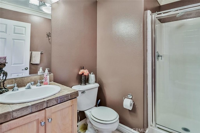 full bath with a stall shower, ornamental molding, toilet, vanity, and baseboards