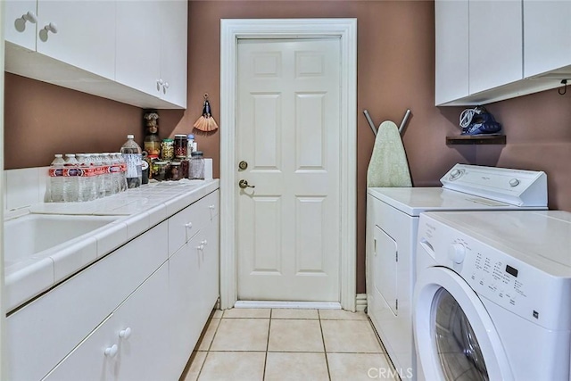 laundry area featuring cabinet space, separate washer and dryer, and light tile patterned floors