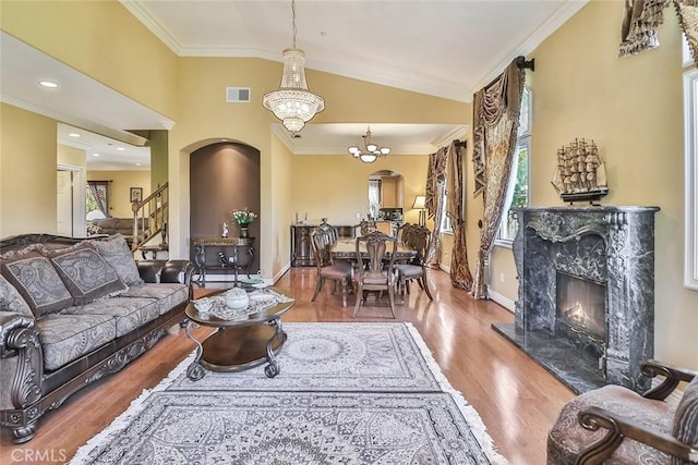living area with arched walkways, a premium fireplace, crown molding, wood finished floors, and baseboards
