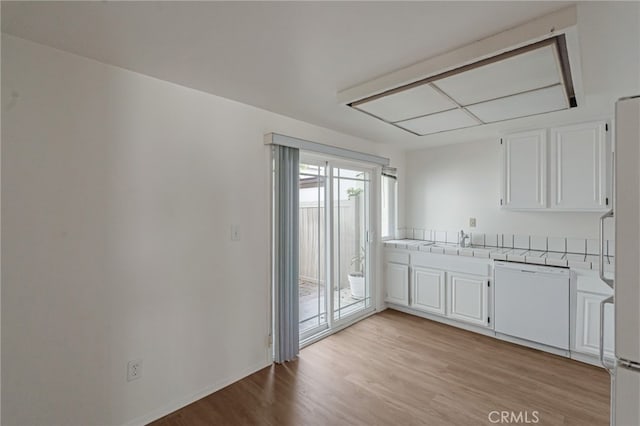 kitchen with white appliances, tile counters, a sink, light wood-style floors, and white cabinetry