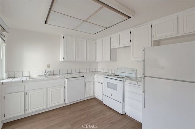 kitchen featuring white appliances, white cabinetry, tile counters, light wood-style flooring, and a sink