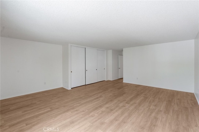 empty room featuring light wood-type flooring and a textured ceiling