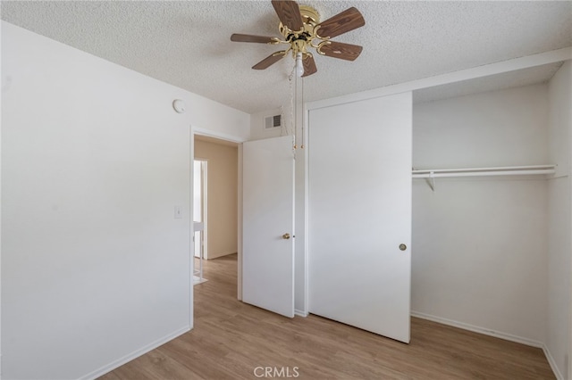unfurnished bedroom featuring wood finished floors, a closet, a textured ceiling, baseboards, and ceiling fan