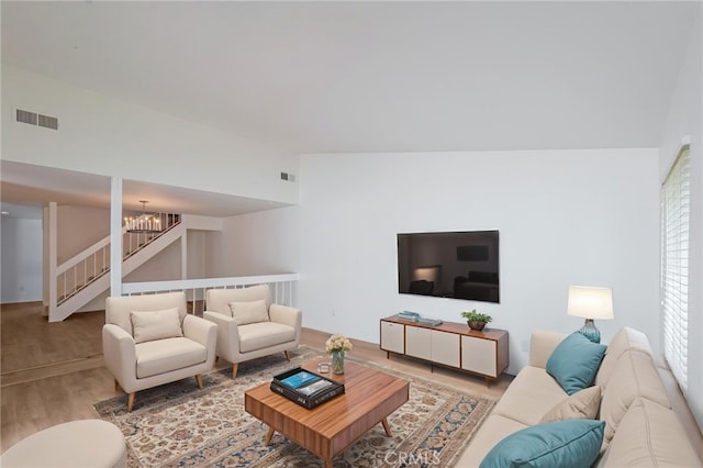 living area featuring a chandelier, wood finished floors, and stairway
