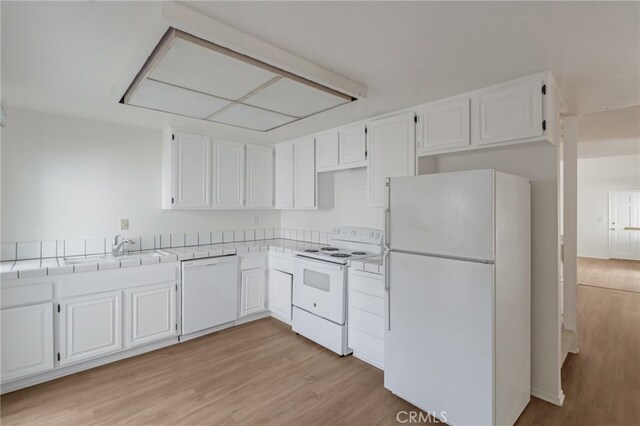 kitchen featuring white appliances, tile countertops, a sink, light wood-type flooring, and white cabinetry
