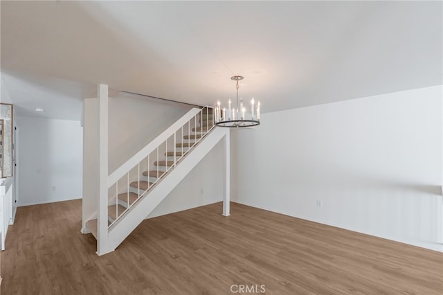 unfurnished dining area with stairway, wood finished floors, and a chandelier