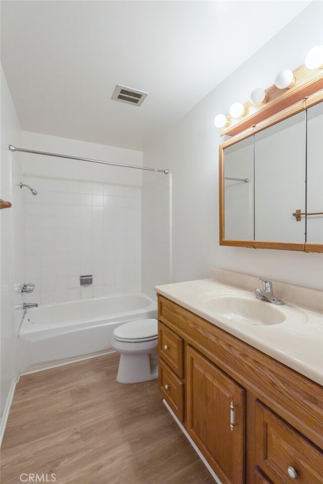 bathroom with wood finished floors, toilet, vanity, and shower / bathtub combination
