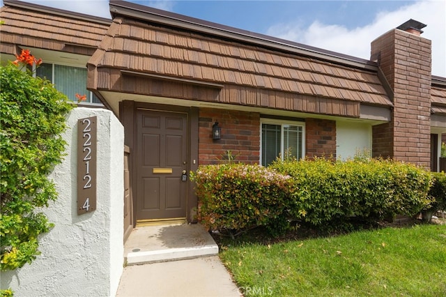 doorway to property with stucco siding and mansard roof