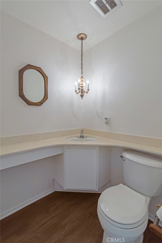 bathroom featuring vanity, wood finished floors, toilet, and a chandelier
