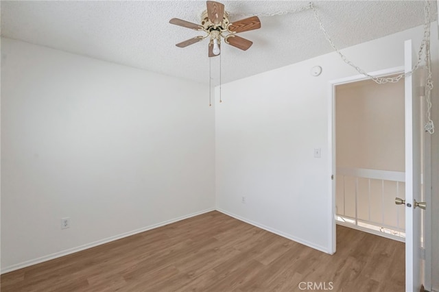 unfurnished room featuring wood finished floors, ceiling fan, a textured ceiling, baseboards, and a smoke detector