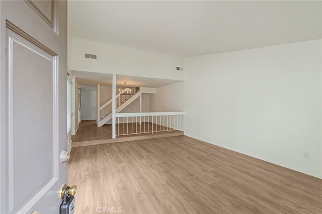 empty room featuring a chandelier, light wood-style floors, and stairs