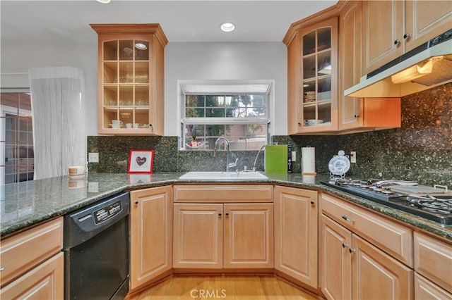 kitchen featuring black appliances, under cabinet range hood, a sink, dark stone countertops, and backsplash