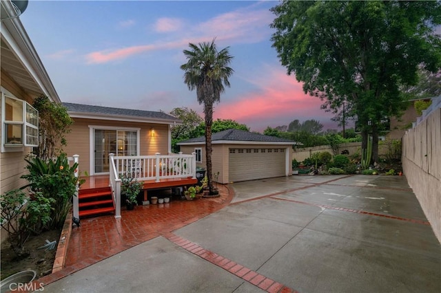 view of front of home featuring a garage, a wooden deck, fence, and an outbuilding
