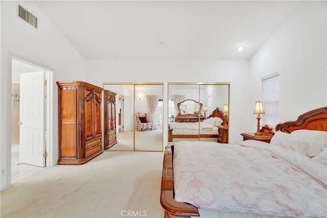 bedroom with light carpet and two closets