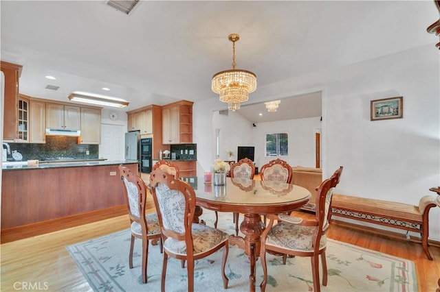 dining space featuring light wood-style floors, a chandelier, and recessed lighting
