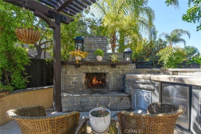 view of patio / terrace featuring an outdoor stone fireplace, fence, and a pergola