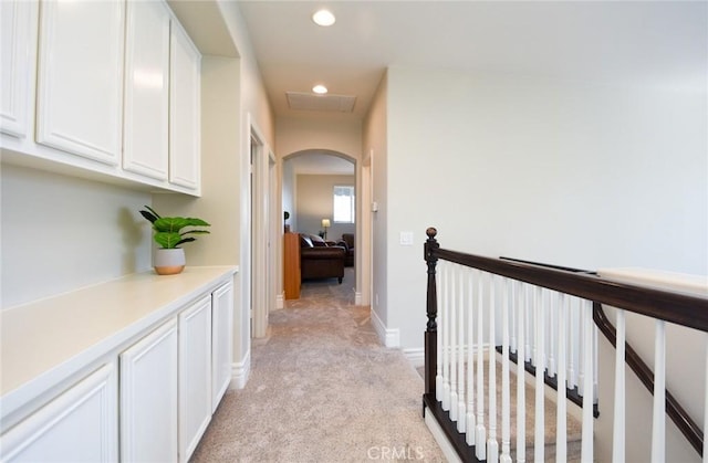corridor featuring recessed lighting, arched walkways, light colored carpet, an upstairs landing, and baseboards