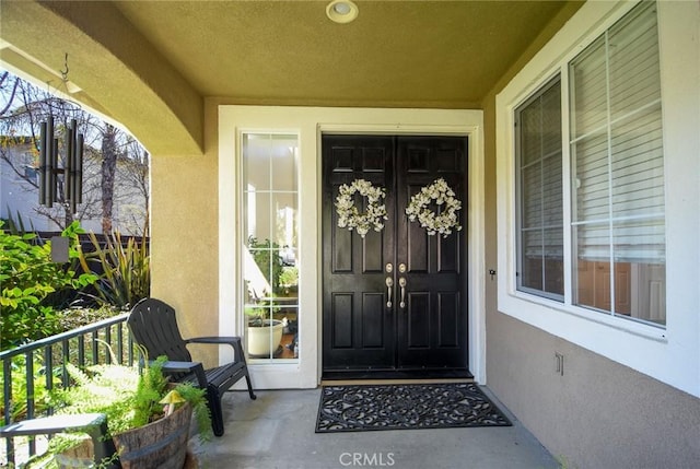 property entrance featuring stucco siding and french doors