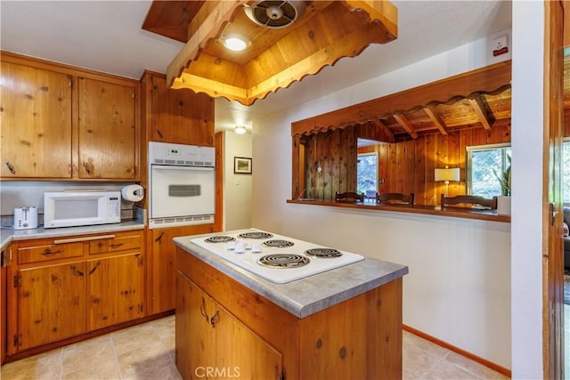26220 Pine Dell Rd, Idyllwild, CA 92549 - kitchen featuring white appliances, brown cabinetry, light tile patterned flooring, a center island, and wooden walls
