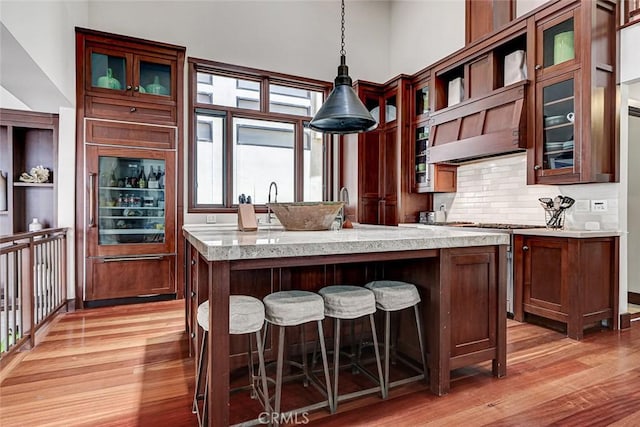 436 32nd St, Manhattan Beach, CA 90266 - kitchen featuring light wood-style flooring, stainless steel gas range oven, decorative backsplash, exhaust hood, and hanging light fixtures
