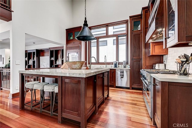 436 32nd St, Manhattan Beach, CA 90266 - kitchen with stainless steel appliances, light wood-type flooring, custom range hood, a breakfast bar area, and backsplash