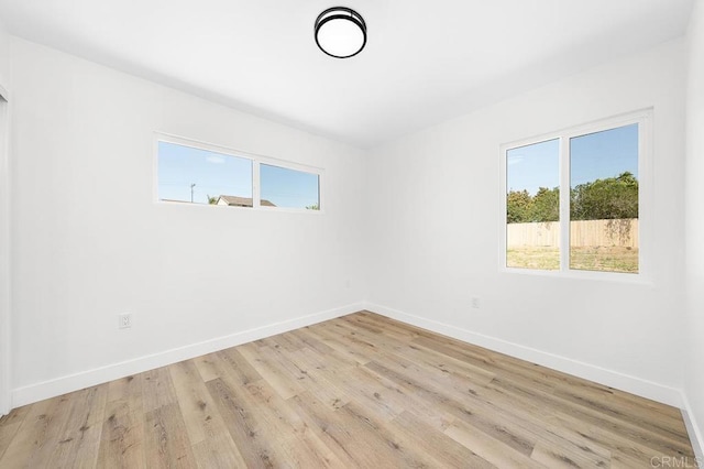 unfurnished room with healthy amount of natural light, baseboards, and light wood-style floors