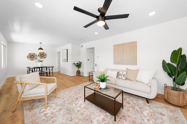 living area featuring light wood finished floors, a ceiling fan, baseboards, and recessed lighting