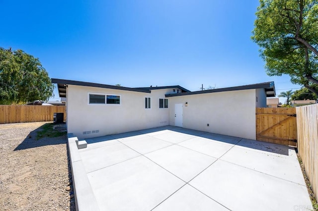rear view of property featuring a patio area, fence, and stucco siding