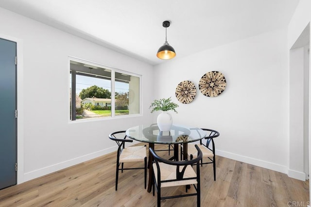 dining space with light wood-type flooring and baseboards