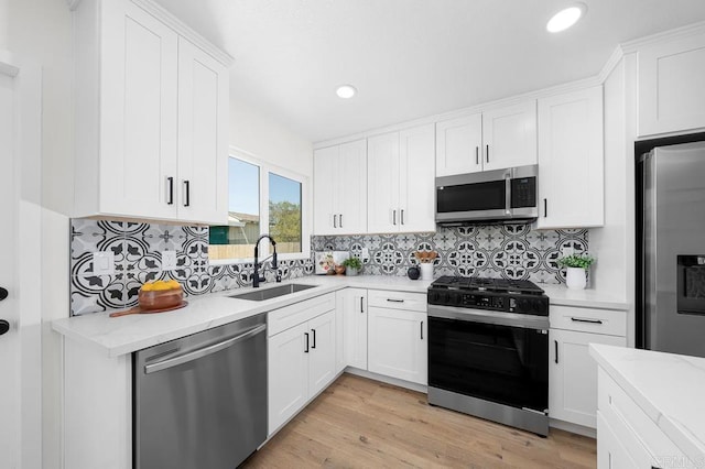 kitchen with appliances with stainless steel finishes, a sink, white cabinetry, tasteful backsplash, and recessed lighting