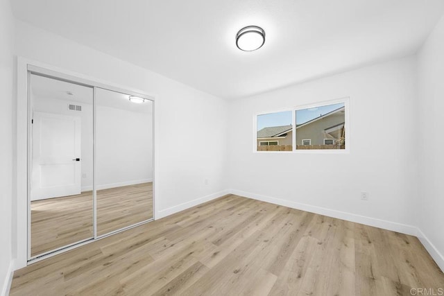 unfurnished bedroom with a closet, light wood-style flooring, and baseboards