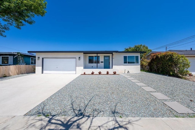 ranch-style house featuring stucco siding, a garage, driveway, and fence