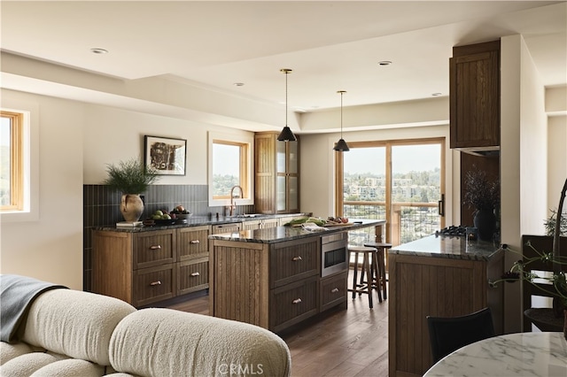 kitchen with dark wood finished floors, dark stone countertops, a center island, oven, and recessed lighting