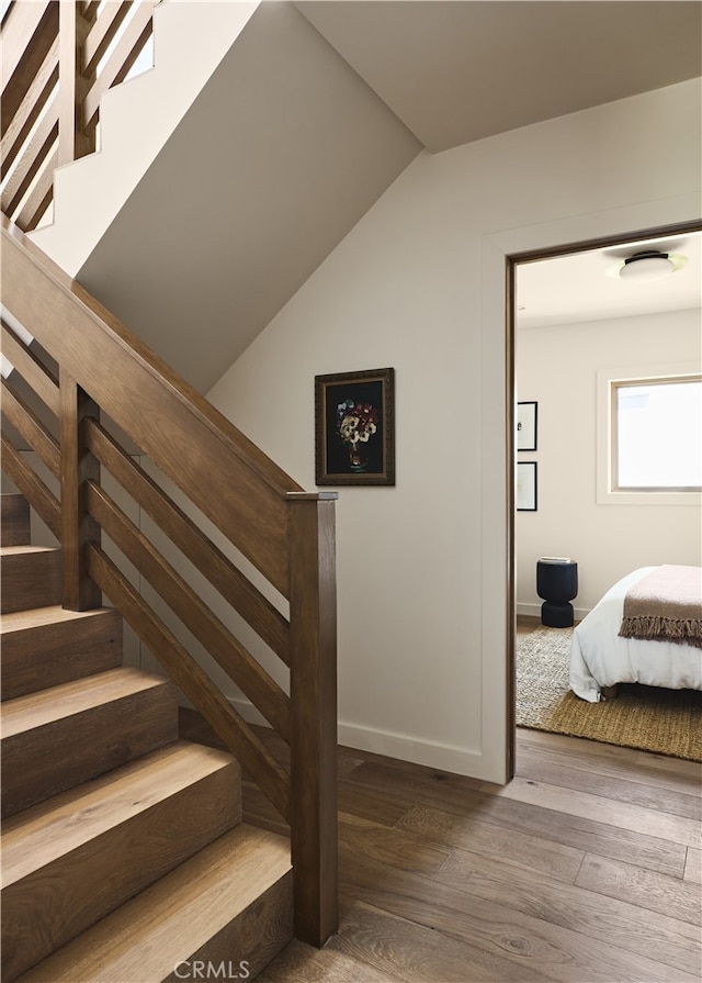 stairway with wood finished floors, baseboards, and lofted ceiling