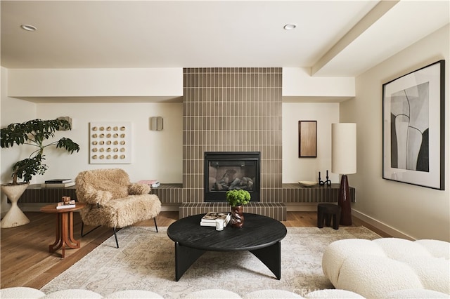 living area with wood finished floors, a fireplace, recessed lighting, and baseboards