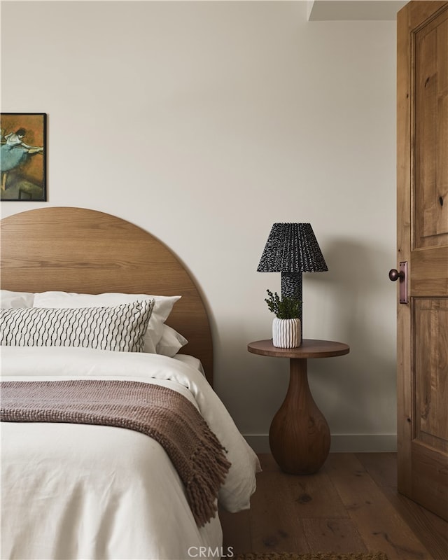 bedroom featuring wood-type flooring and baseboards