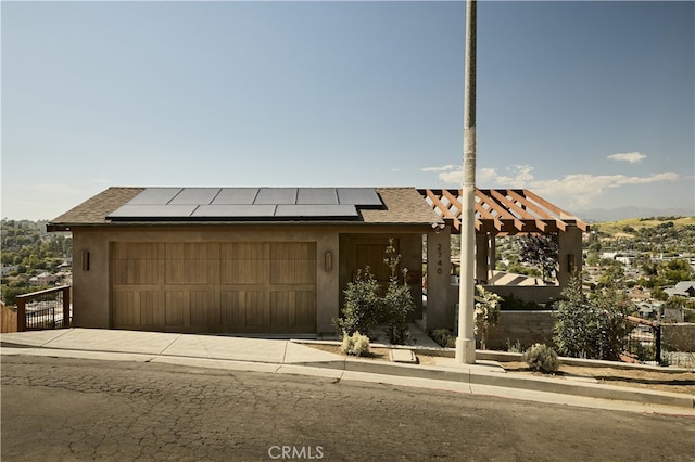 view of front of house featuring roof mounted solar panels, an attached garage, a shingled roof, driveway, and stucco siding