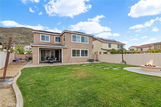 24521 Snapdragon Way, Lake Elsinore, CA 92532 - back of property with an outdoor fire pit, stucco siding, roof mounted solar panels, and a patio