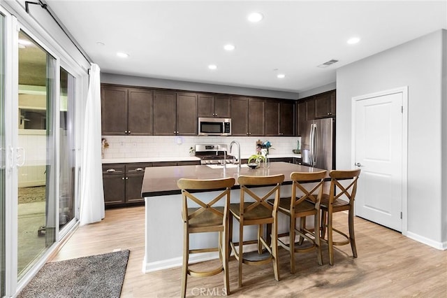24521 Snapdragon Way, Lake Elsinore, CA 92532 - kitchen with stainless steel appliances, dark brown cabinetry, tasteful backsplash, a center island with sink, and recessed lighting